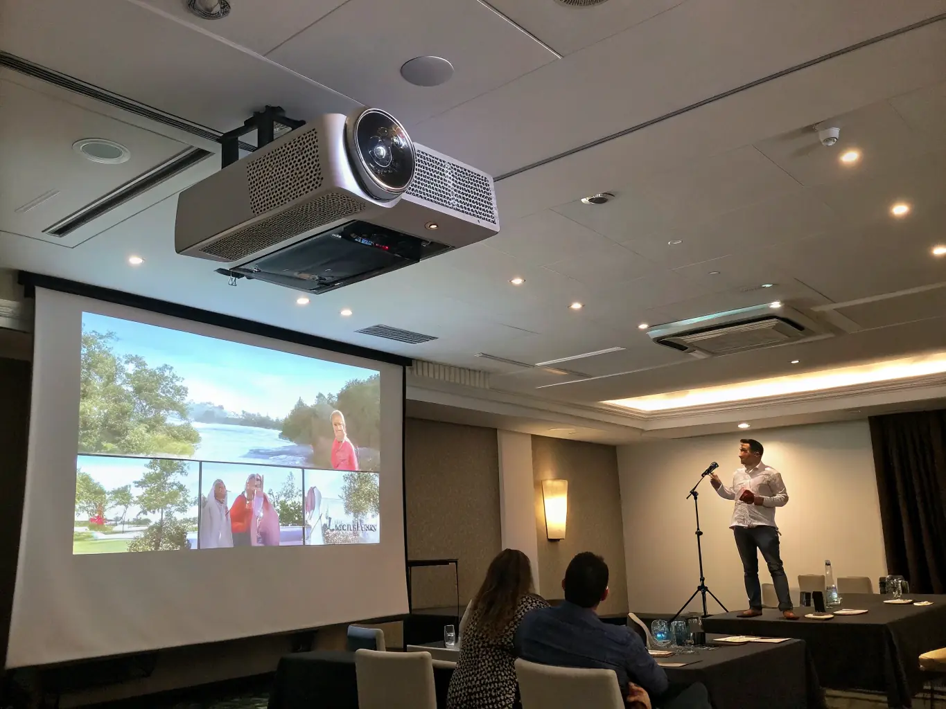 A high-definition projector screen displaying a crisp and clear presentation slide in a dimly lit conference room, showcasing its excellent image quality and suitability for professional events.